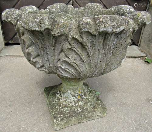 A weathered cast composition stone garden urn with circular ...