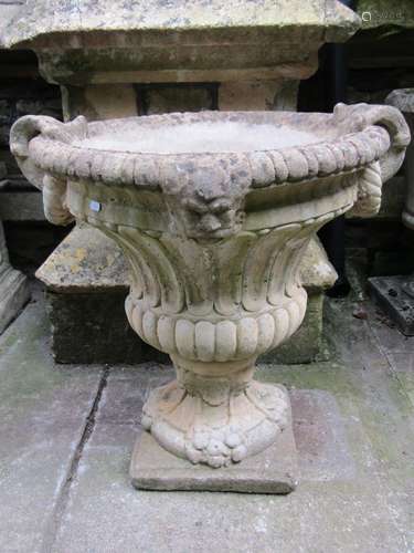 A weathered cast composition stone garden urn with circular ...