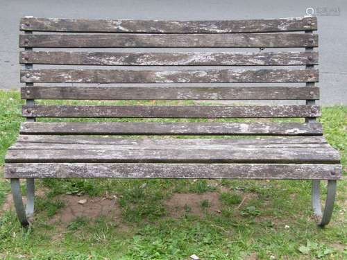 A vintage garden bench with weathered timber lathes raised o...