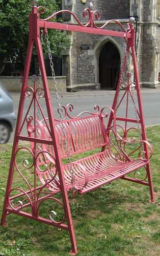 An iron work two seat garden swing with strapwork seat and b...