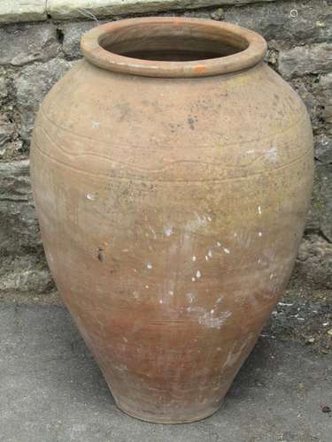 A weathered terracotta oviform urn/jar with simple incised b...