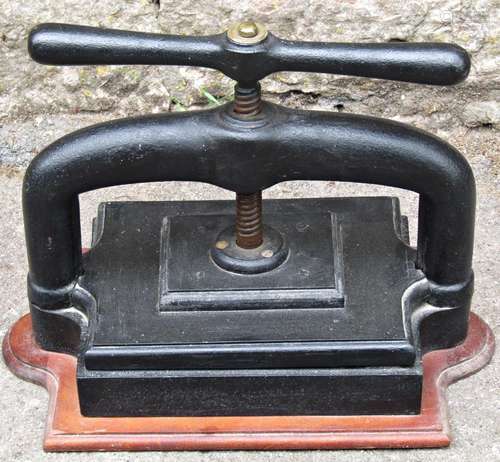 A vintage cast iron book press with central screw thread and...