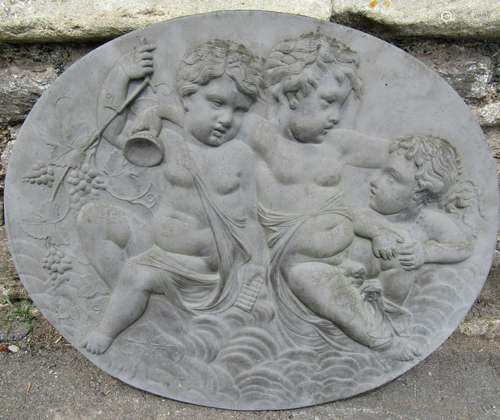 A cast oval wall plaque with frolicking cherub raised relief...