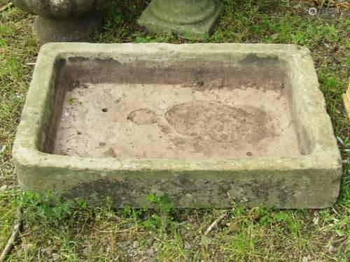 A weathered natural stone trough of shallow rectangular form...