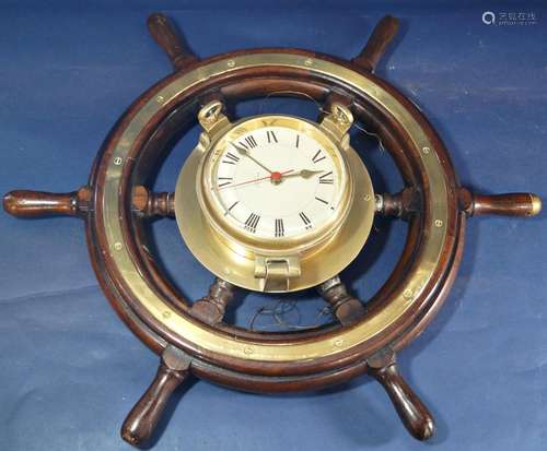 An old ships wheel in teak with brass mounts, supporting a l...