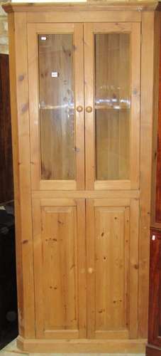 A stripped pine floorstanding corner cabinet enclosed by two...