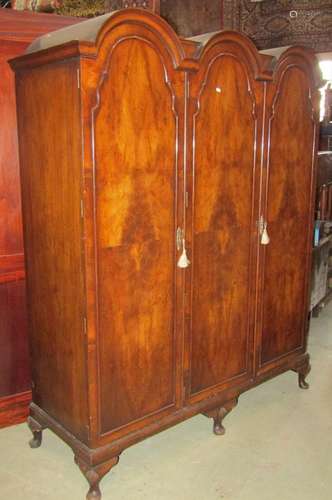 A walnut veneered triple wardrobe in the Queen Ann style, th...