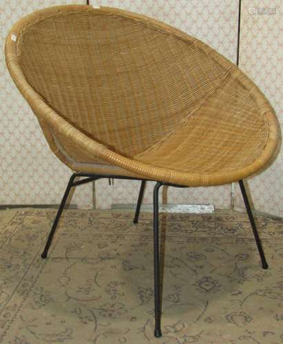 A vintage wicker cone chair raised on tubular steel supports...