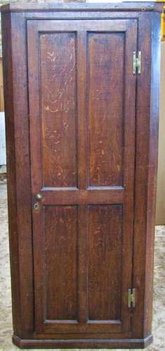 A Georgian oak floorstanding corner cupboard enclosed by a f...