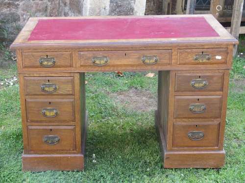 An Edwardian oak pedestal writing desk of nine drawers with ...