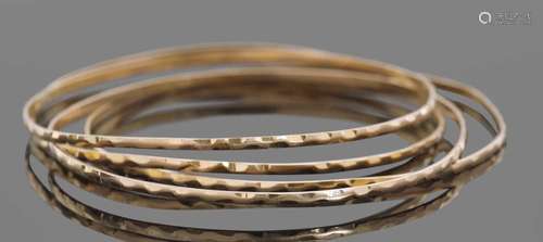 Four mid-grade yellow metal bangles with engraved detail, 19...