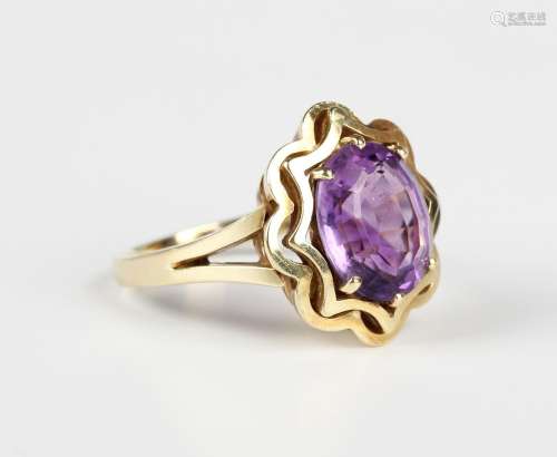 A gold ring, claw set with an oval cut amethyst within a sha...