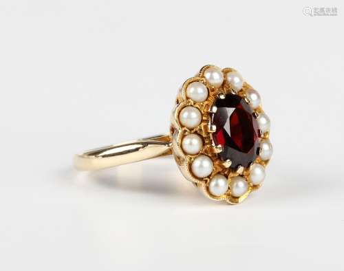 A gold ring, claw set with an oval cut garnet within a surro...