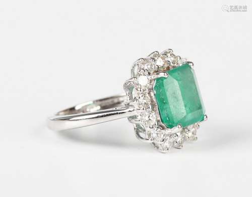 A white gold, emerald and diamond cluster ring, claw set wit...