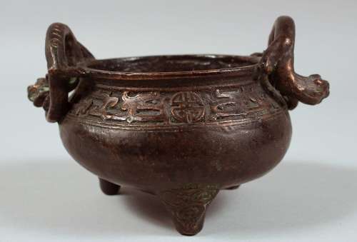 A CHINESE BRONZE TWIN HANDLE TRIPOD CENSER, the handles form...