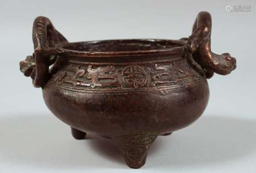 A CHINESE BRONZE TWIN HANDLE TRIPOD CENSER, the handles form...