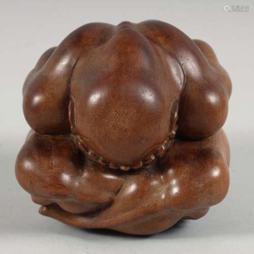 A CHINESE HARDWOOD CARVING OF A HUNCHED FIGURE, his head in ...