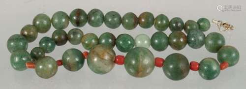 A SET OF GRADUATED JADE BEADS, the larger beads with small c...