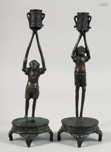 A PAIR OF JAPANESE BRONZE CANDLESTICKS, formed as figures ho...