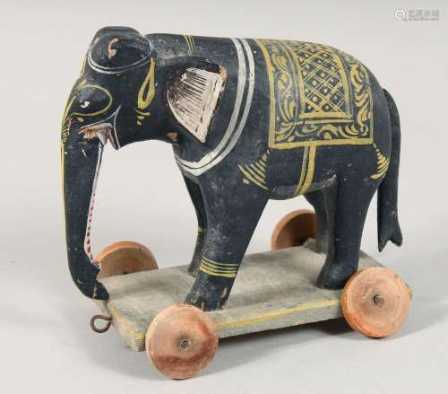 A CARVED INDIAN WOODEN TOY ELEPHANT ON WHEELS, 18cm long.