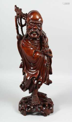 A LARGE CHINESE CARVED HARDWOOD FIGURE OF A SAGE holding a s...