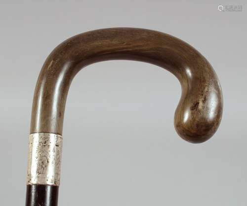 AN ANTIQUE RHINO HORN HANDLE WALKING STICK, with silver band...