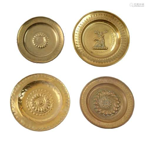A GROUP OF FOUR EMBOSSED BRASS CHARGERS OR ALMS DISHES