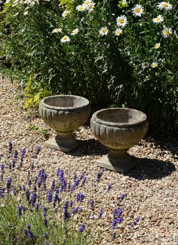 A PAIR OF STONE COMPOSITION GARDEN URNS