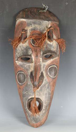 An African carved mask with applied grass tassels