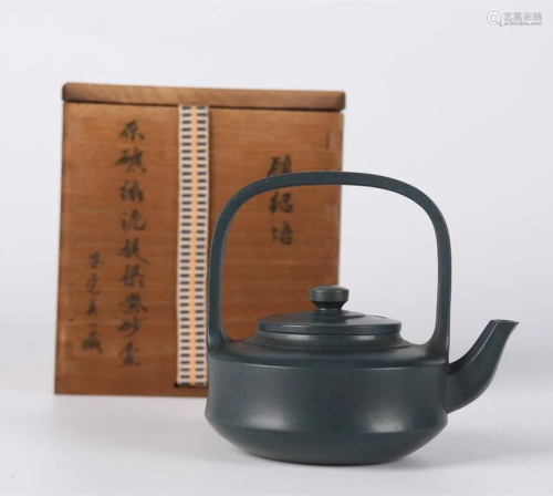 A PURPLE CLAY TEAPOT WITH LOOP HANDLE.