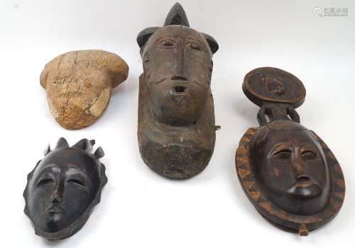 Four African masks, to include a mask with elaborate coiffur...