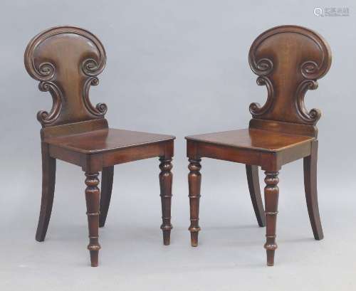A pair of Victorian mahogany hall chairs, the carved back wi...