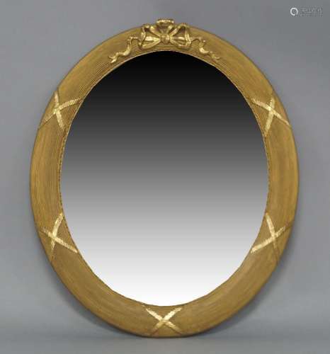 An oval giltwood mirror, 20th century, with ribbon crest, re...