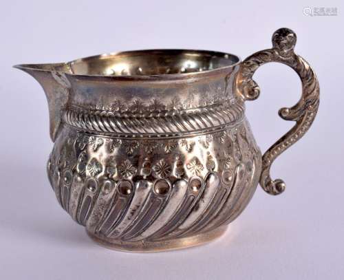 AN EMBOSSED STERLING SILVER CREAM JUG BY CHARLES STUART HARR...
