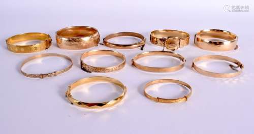 ELEVEN ROLLED GOLD BANGLES. Largest 5.8cm x 5.2cm, total wei...