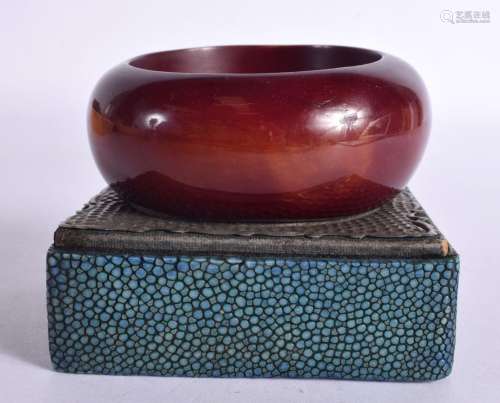A CHERRY AMBER TYPE BANGLE upon a shagreen stand. 7.5 cm dia...