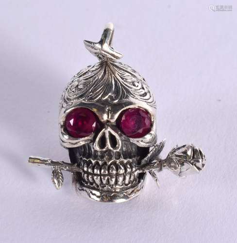 A WHITE METAL SKULL PENDANT WITH GEM SET EYES AND A ROSE BET...