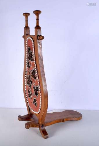 An early 20th Century wooden boot pull with an embroidered p...