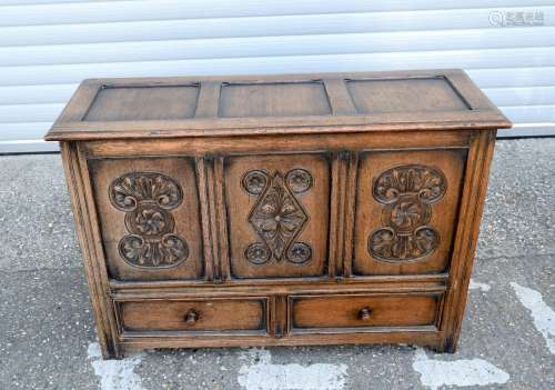 A large oak hinged lid chest with two drawers and carved pan...
