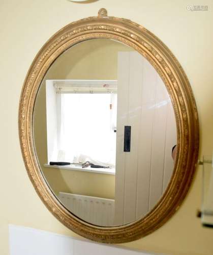 A COUNTRY HOUSE OVAL GILTWOOD MIRROR. 66 cm x 54 cm.