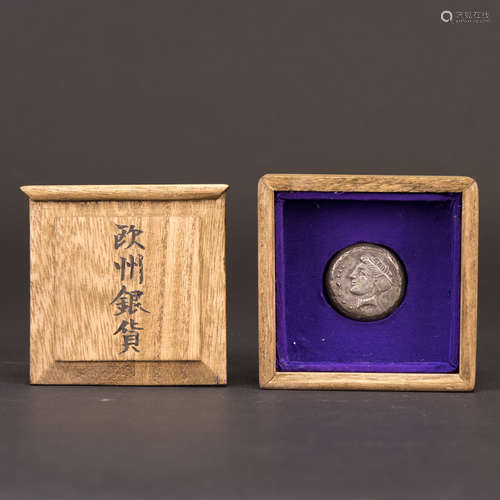 A SILVER COIN WITH JAPANESE BOX