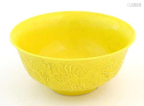 A Chinese bowl with a yellow ground decorated in relief with...