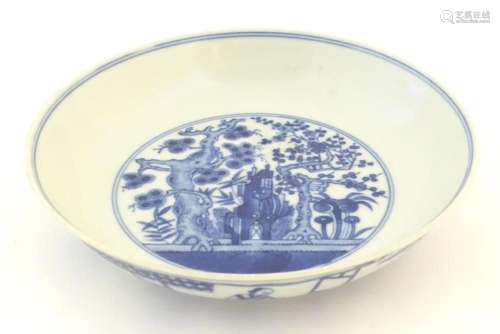 A Chinese blue and white plate decorated with trees and flow...
