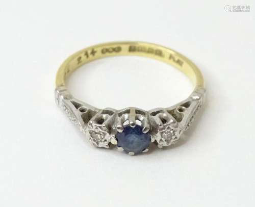 An 18ct gold ring set with central sapphire flanked by diamo...