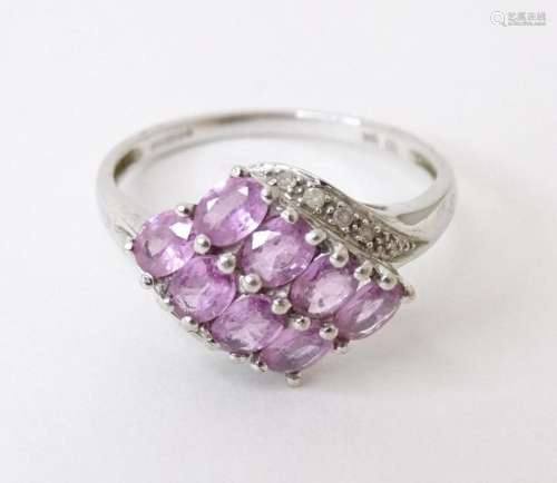 A 9ct white gold ring set with 8 pink sapphires flanked by d...