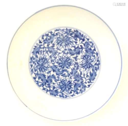 A Chinese blue and white plate decorated with scrolling flor...