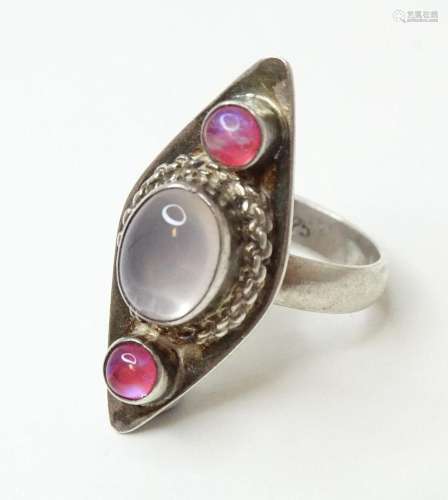 A silver ring set with central moonstone cabochon flanked by...