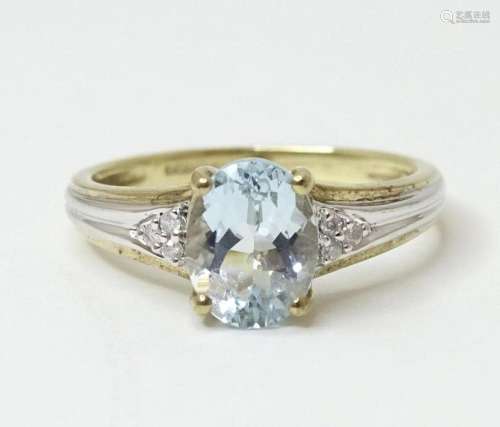 A 9ct gold ring set with central oval facet cut aquamarine f...