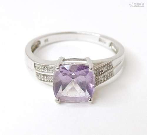 A 9ct white gold ring set with central amethyst flanked by d...