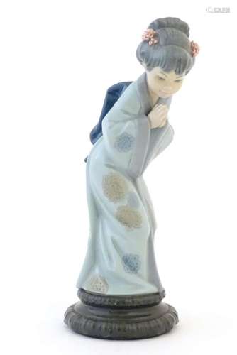 A Lladro model of a Japanese Geisha girl bowing with her han...